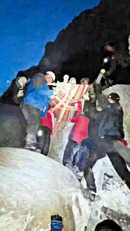 救援隊(duì)員用自制的簡(jiǎn)易擔(dān)架抬傷者。